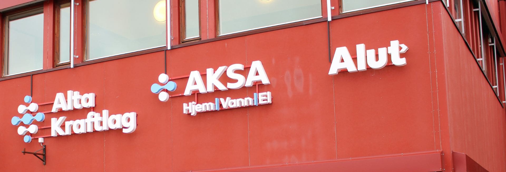 Bilde viser utsiden av lokalet til Alta Kraftlag, og logoene på navnene til selskapene: Alta Kraftlag, Aksa Hjem, Vann, El, og Alut
